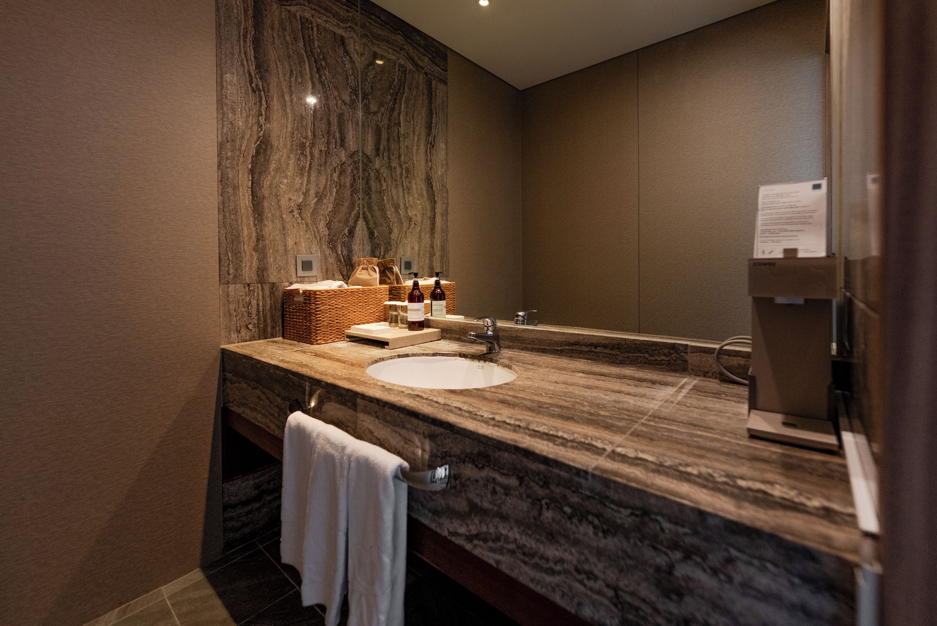 A bathroom with a marble sink, a large mirror, and a towel rack.