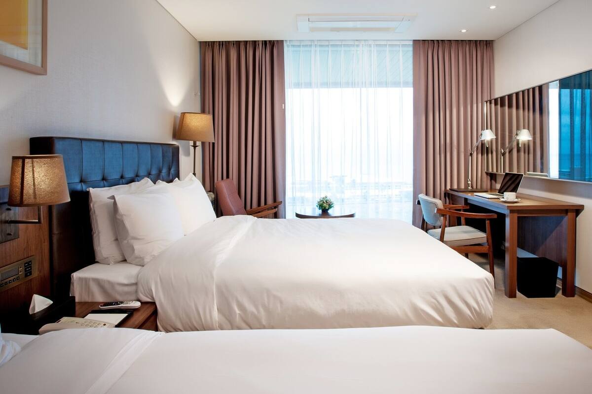 Een hotelkamer met twee bedden, een bureau en een stoel.