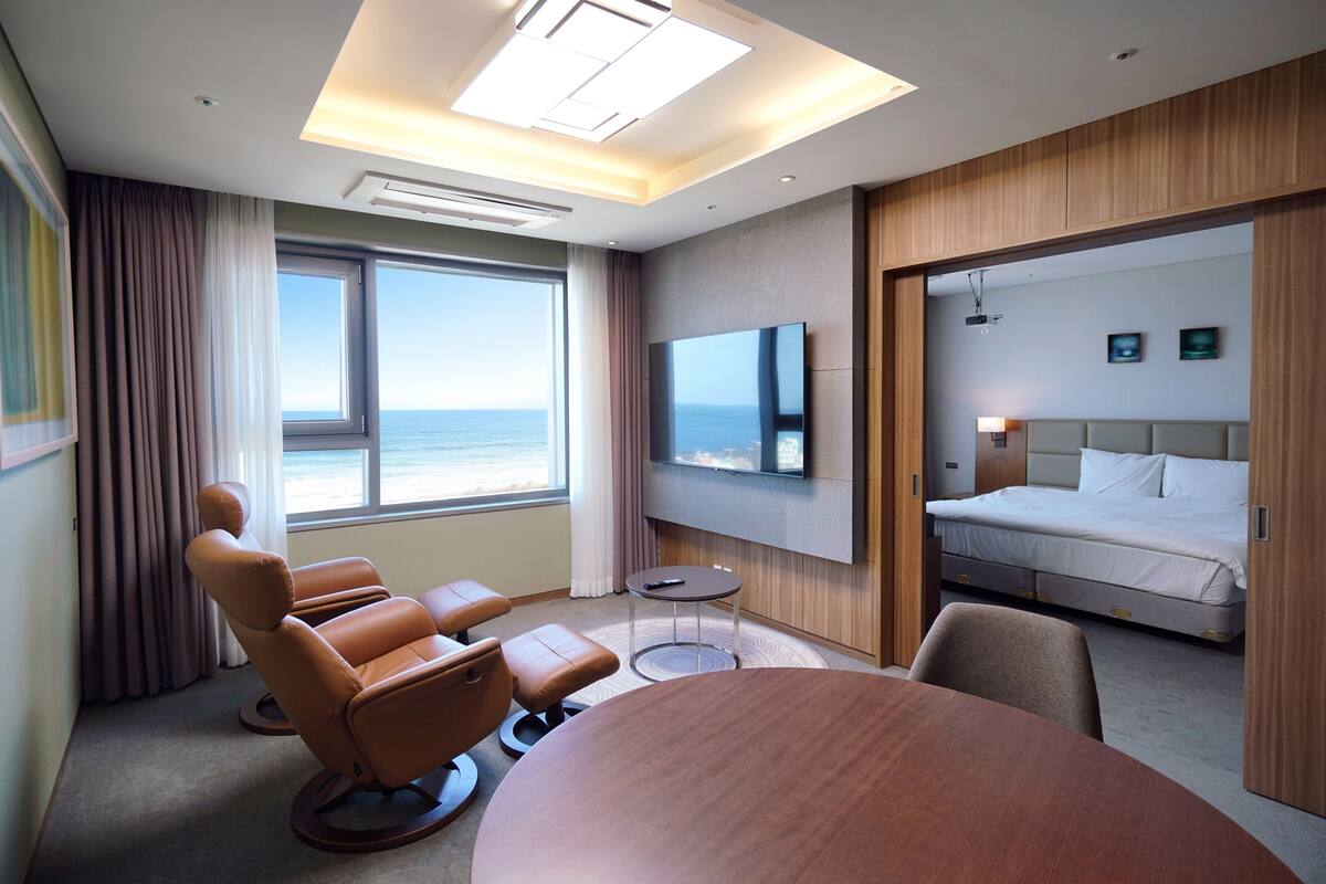 Hotelkamer met een groot raam, een flatscreen televisie, een bed, een zithoek met stoelen en een ronde tafel.