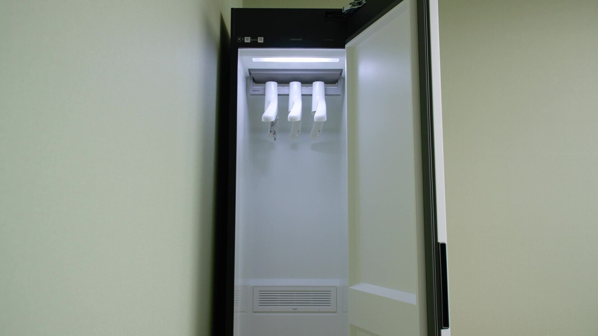 Un couloir étroit et blanc, avec une porte au fond.