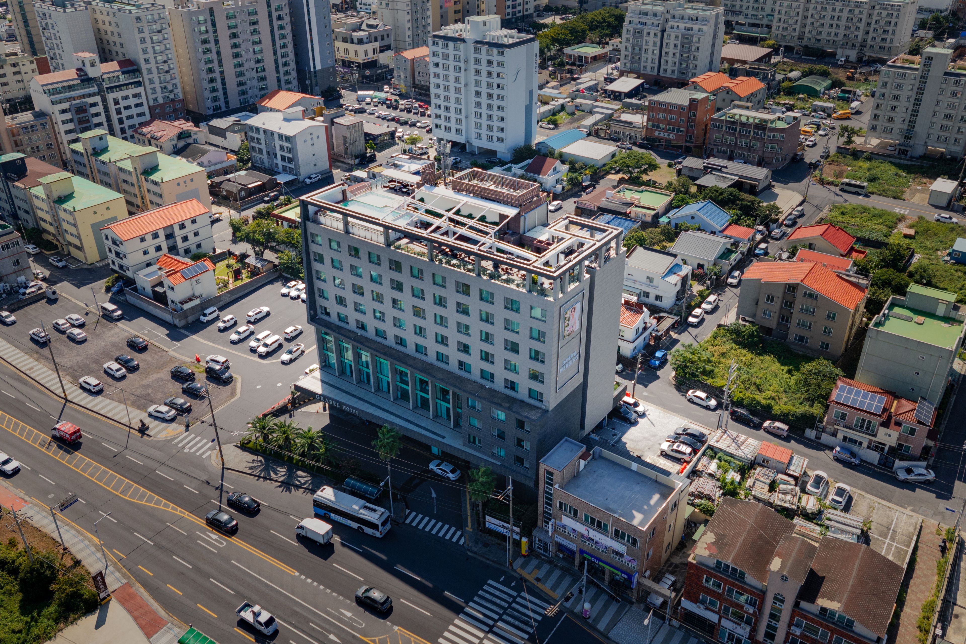 A multi-story hotel with a rooftop terrace, surrounded by a dense urban environment.