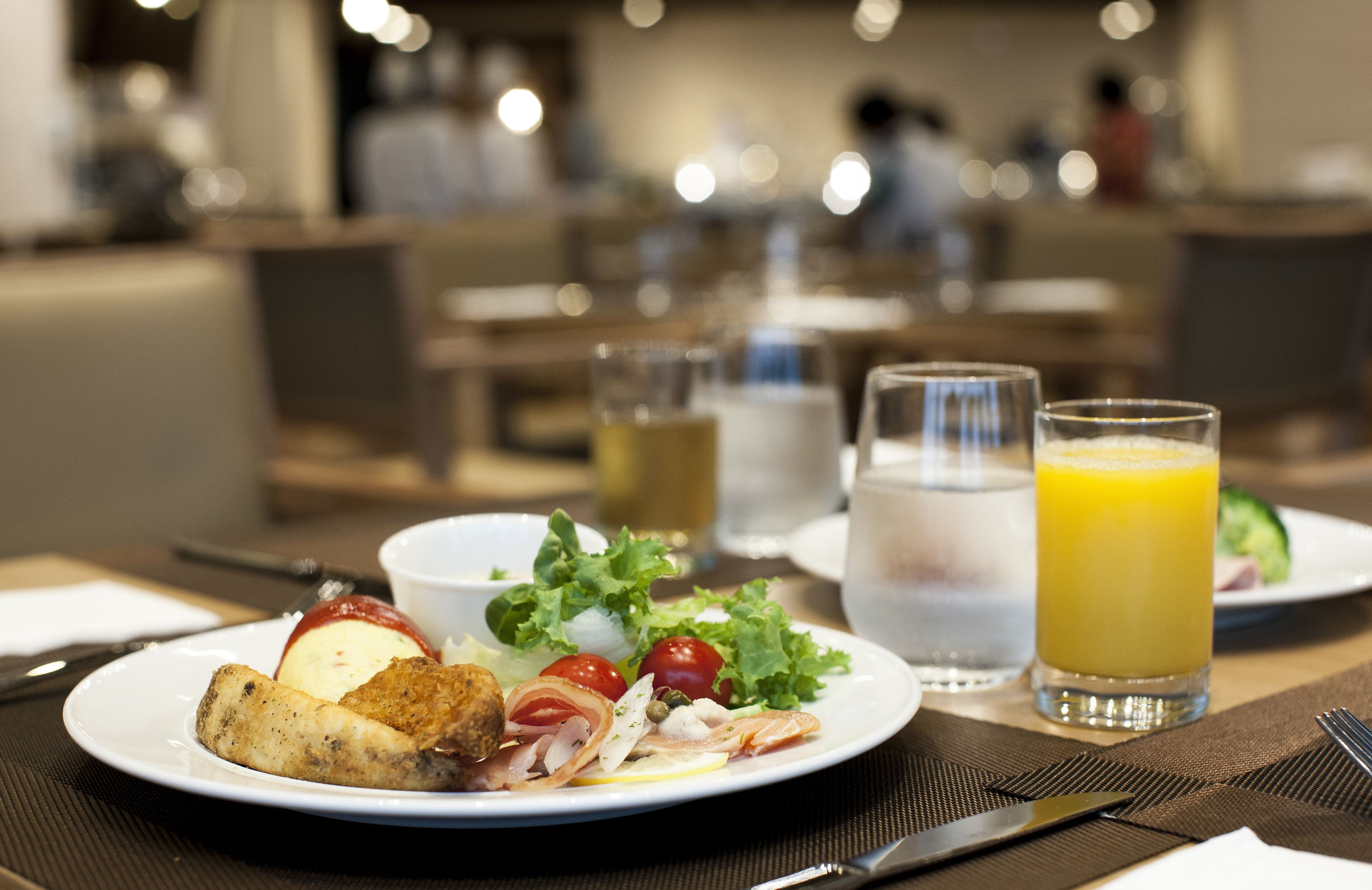A breakfast setting with plates of food, including eggs, bacon, and tomatoes, and glasses of orange juice.