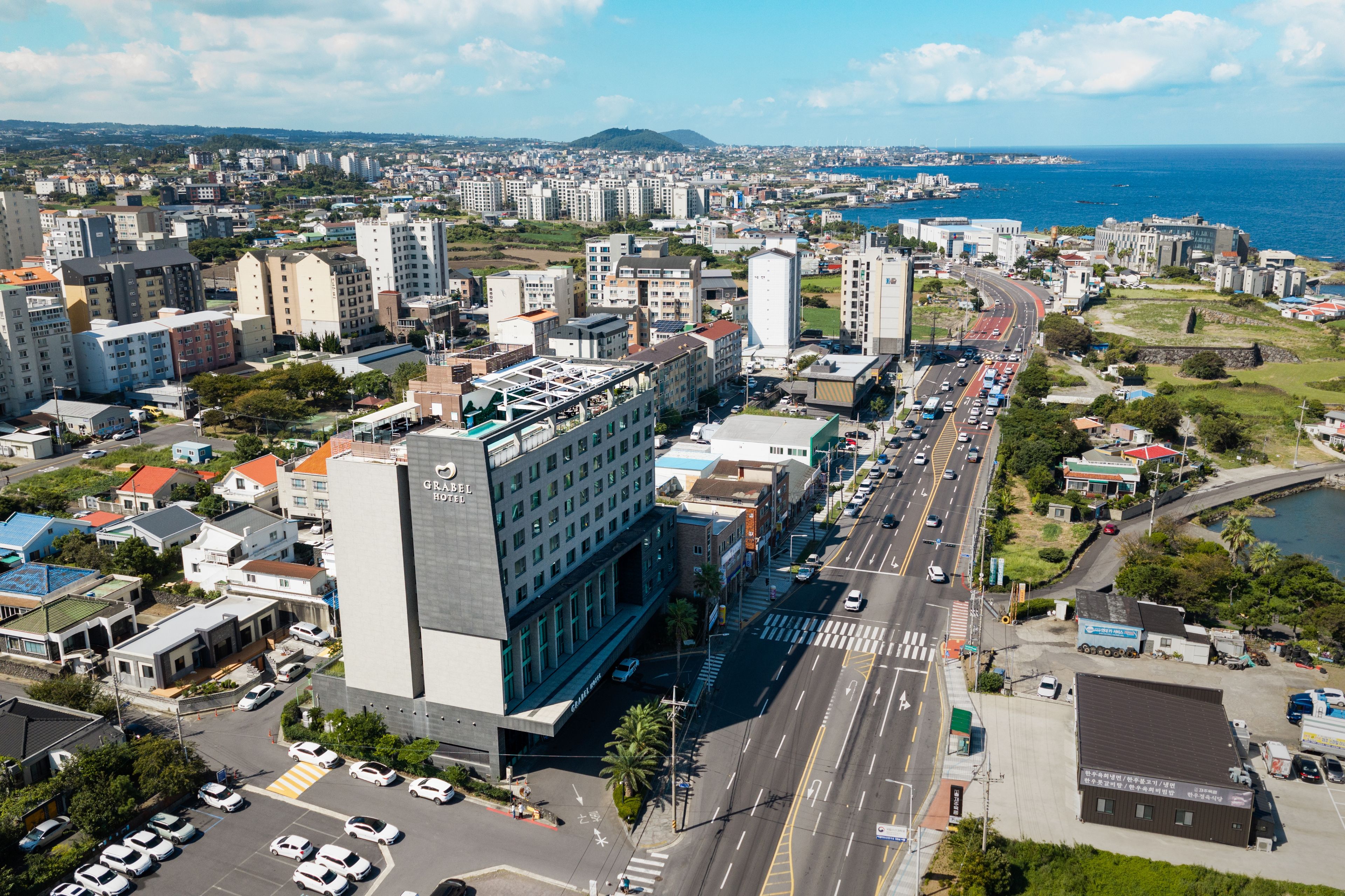 A hotel with a modern design, located near a busy road with a view of the sea.