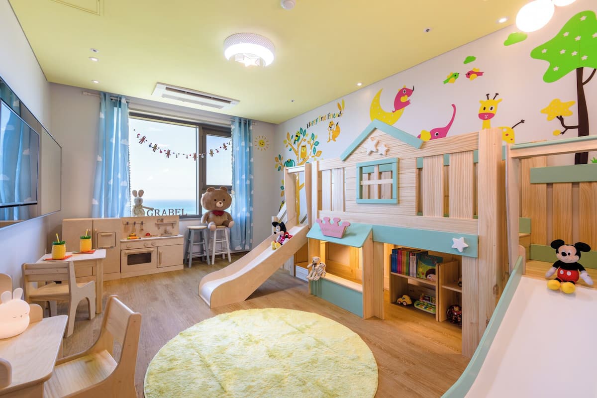 Een kinderspeelruimte met een glijbaan, een keukentje en een boekenkast.