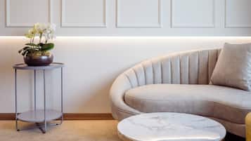 A modern living room with a beige sofa, a round marble coffee table, and a side table with a potted plant.