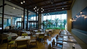 A spacious restaurant with high ceilings, large windows, and a variety of seating arrangements. - Grabel Hotel Jeju (Jeju City)