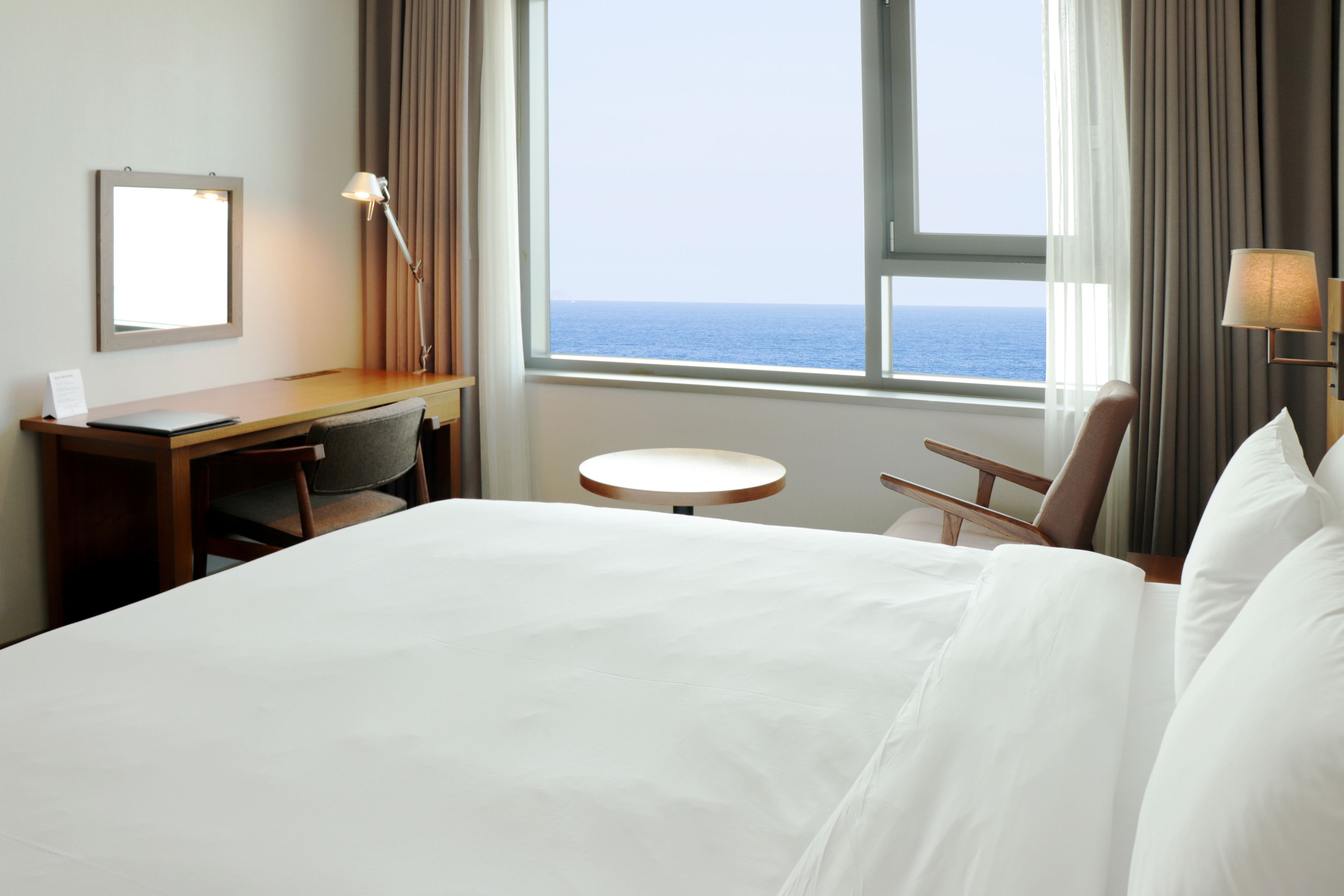 A hotel room with a bed, desk, chair, and a small table.