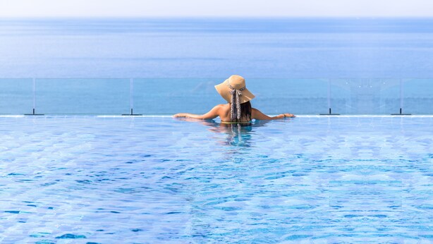 Una mujer en una piscina con vista al océano.