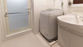 A bathroom with a white sink, a mirror, and a washing machine.