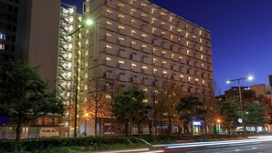 A multi-story hotel with a uniform facade, illuminated windows, and a flat roof.