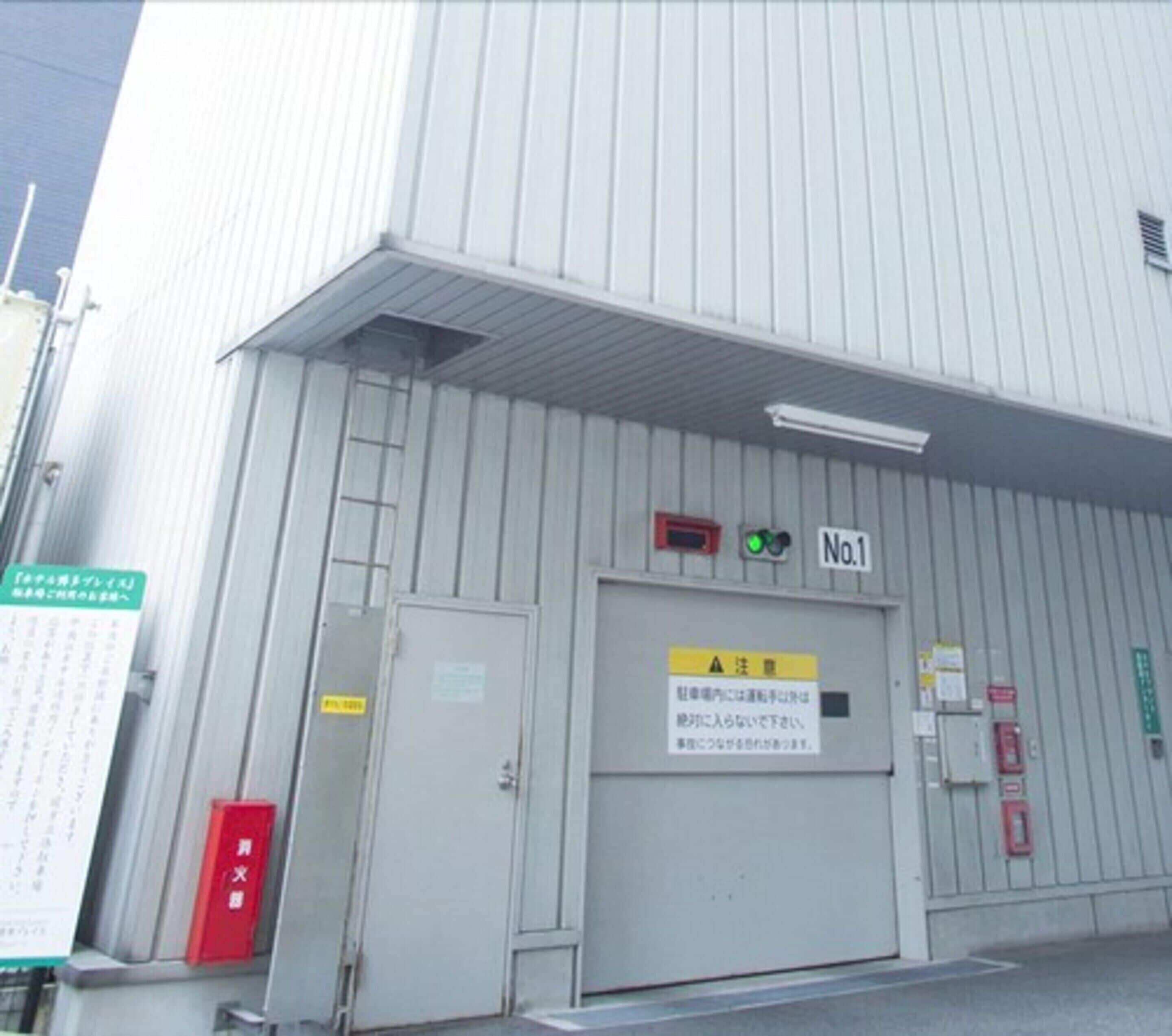 A large industrial building with a grey metal exterior, a door labeled "No.1", and various safety and informational signs.