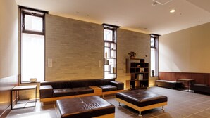A modern living room with a sectional sofa, two ottomans, a coffee table, and a bookshelf.