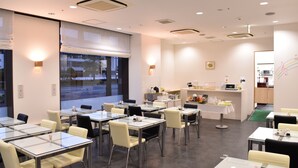 A modern dining area with glass tables and chairs, a kitchen counter, and a view of the outdoors.