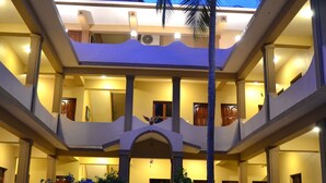 Un edificio de varios pisos con un patio central, balcones y una palmera.