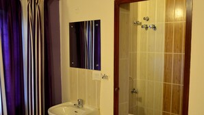 Un baño con lavamanos blanco, espejo, cabina de ducha e inodoro.