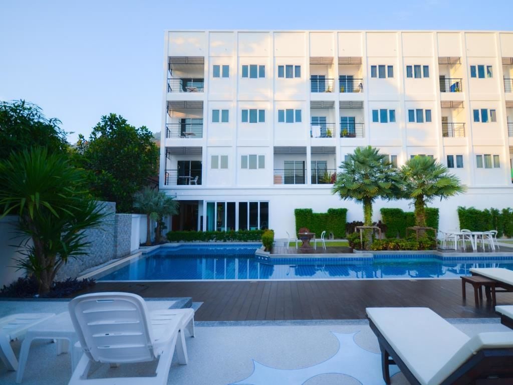 A modern hotel with a pool area, including lounge chairs and a well-maintained garden.