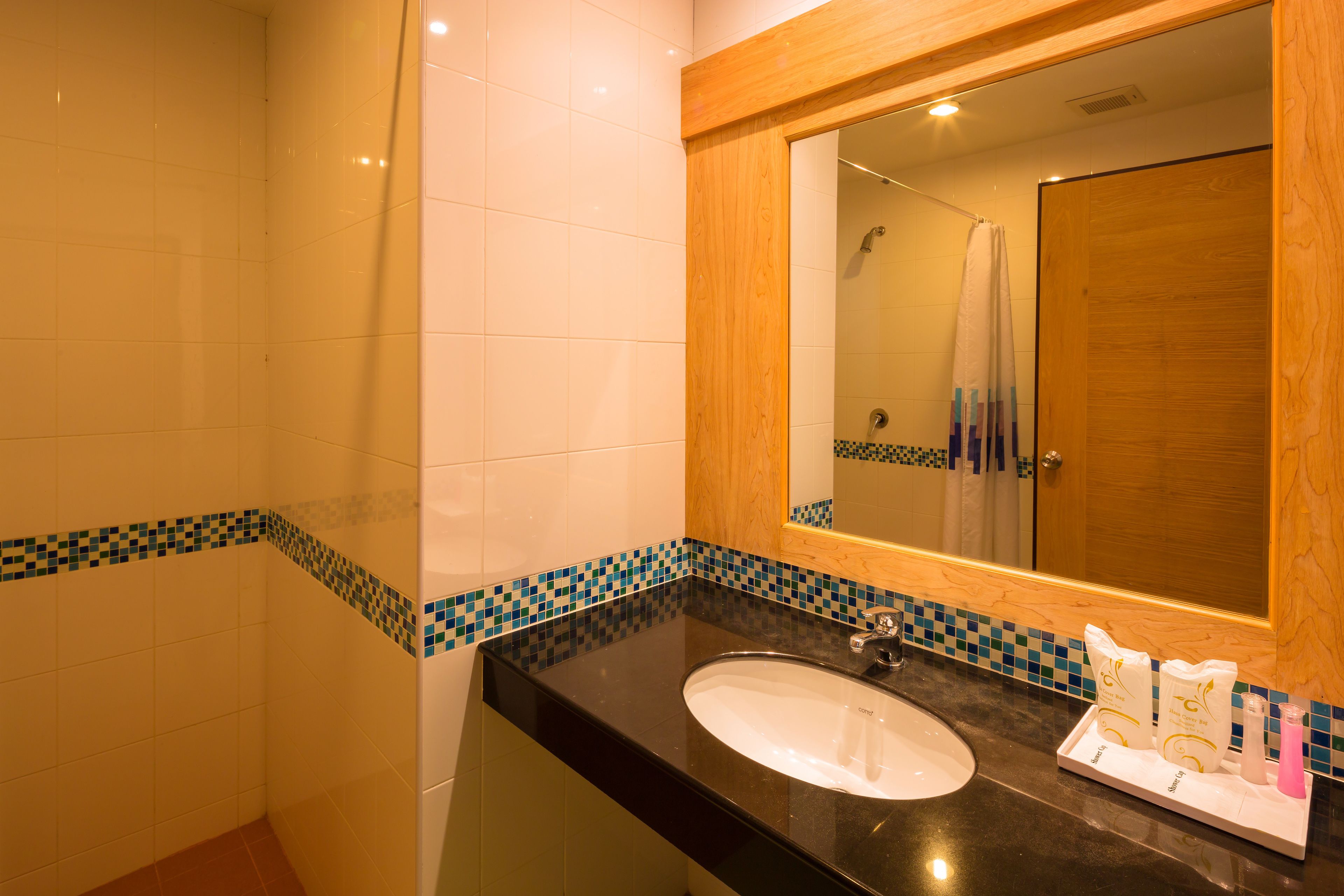 A bathroom with a black sink, white tiles, and a wooden-framed mirror.