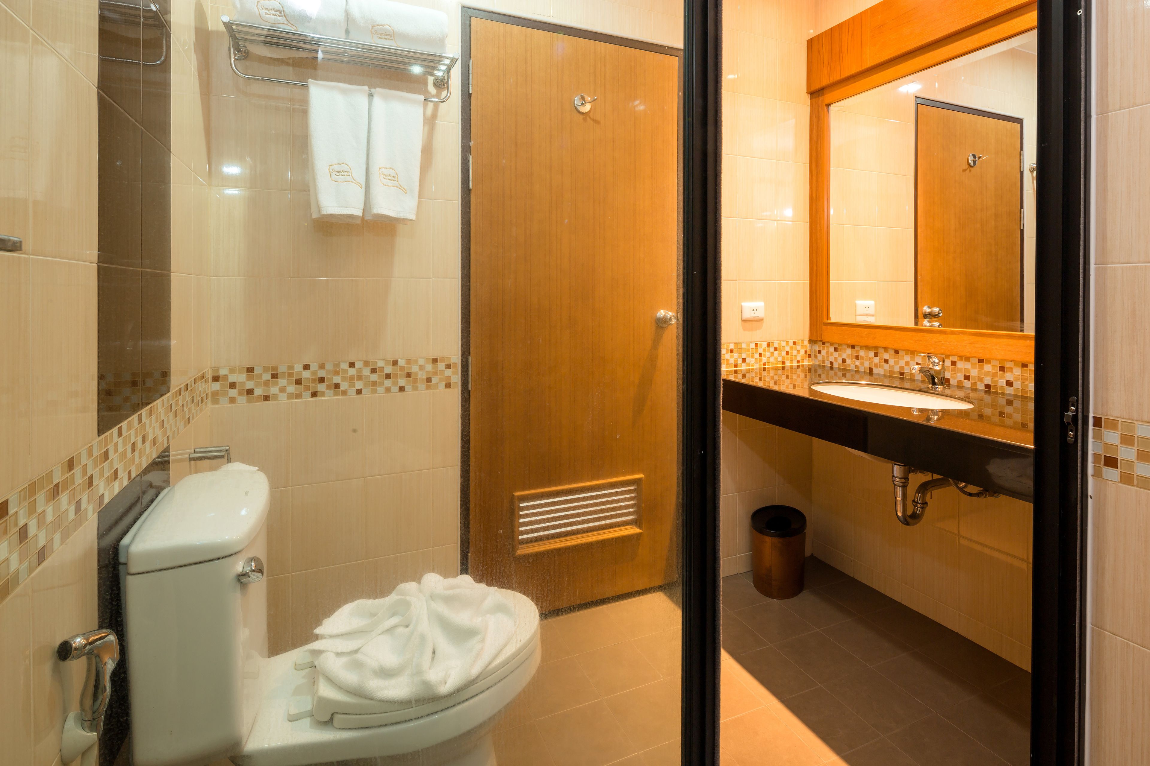 Un baño con inodoro, lavamanos, espejo y paredes de azulejos.