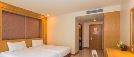 A hotel room with a double bed, a wooden headboard, a desk with a chair, and a mirror.