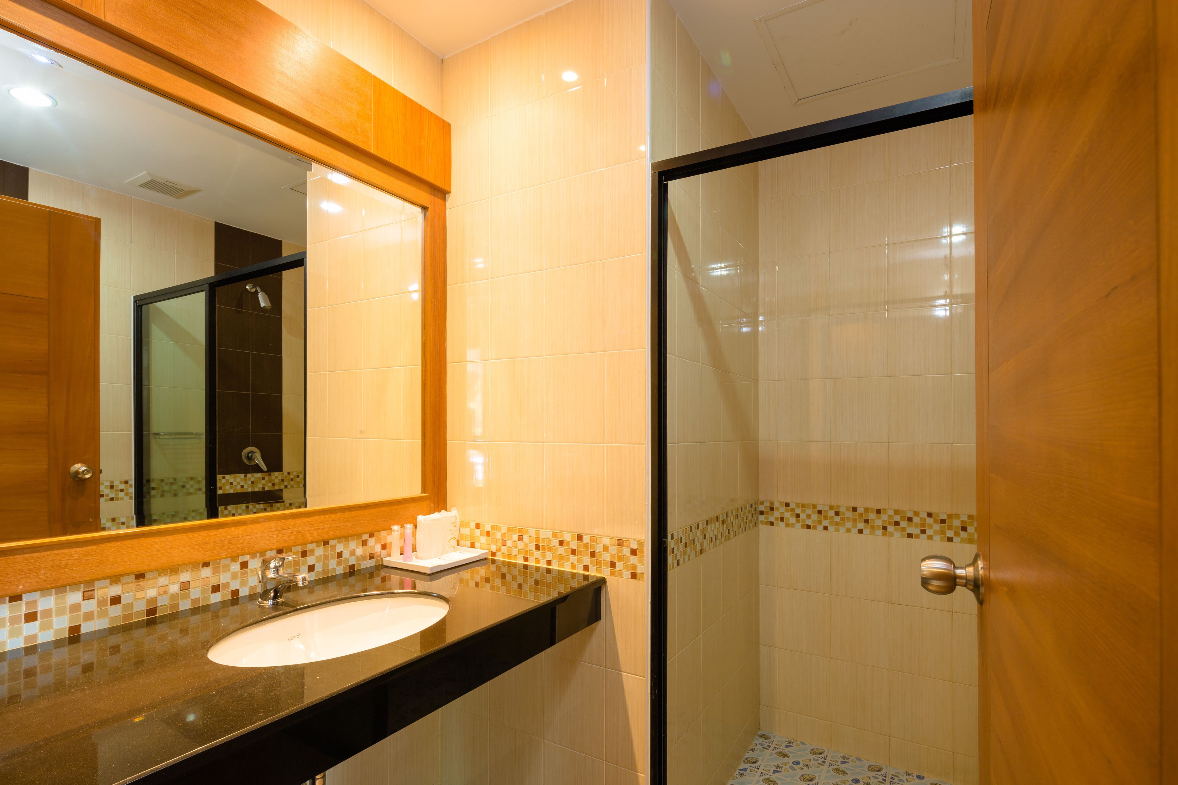 A bathroom with a sink, mirror, and shower area.