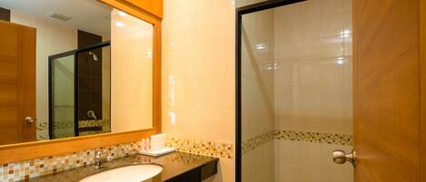 A bathroom with a sink, mirror, and shower area.