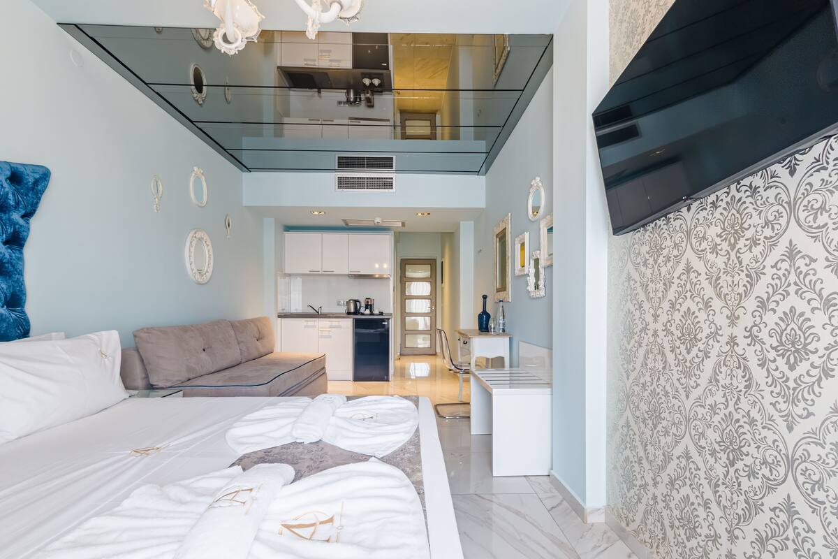 Un dormitorio moderno con una cama grande, un sofá, una kitchenette y un baño.