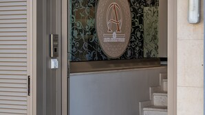 A hotel entrance with a glass door, a staircase leading inside, and a trash can outside. - Alpha Luxury Suites (Kassandra)