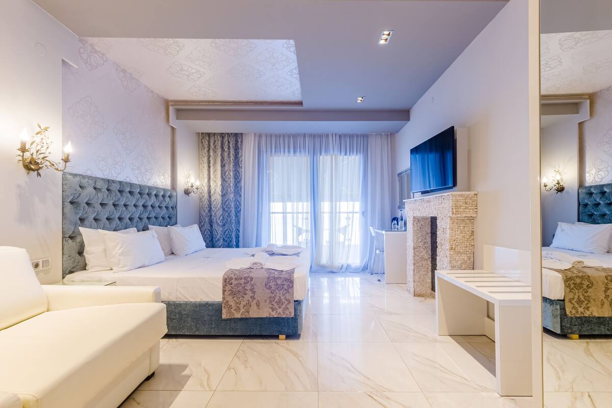 Una habitación de hotel moderna con una cama grande, un sofá, un escritorio pequeño y una chimenea.