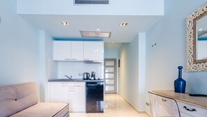A modern kitchen with white cabinets, a stainless steel refrigerator, and a coffee machine. - Alpha Luxury Suites (Kassandra)