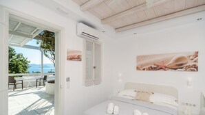 Un dormitorio con cama, mesita de noche y ventana que da a un patio con mobiliario exterior.