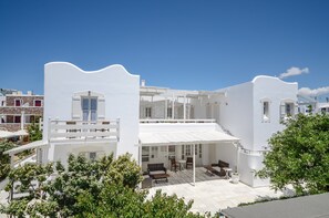 A modern white building with a covered patio area featuring outdoor seating. - Ostria Hotel (Naxos)