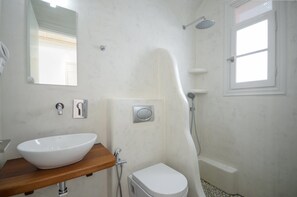 A bathroom with a white sink, toilet, and shower. - Ostria Hotel (Naxos)