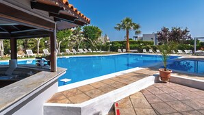 Una piscina con sillas de descanso y una zona cubierta.