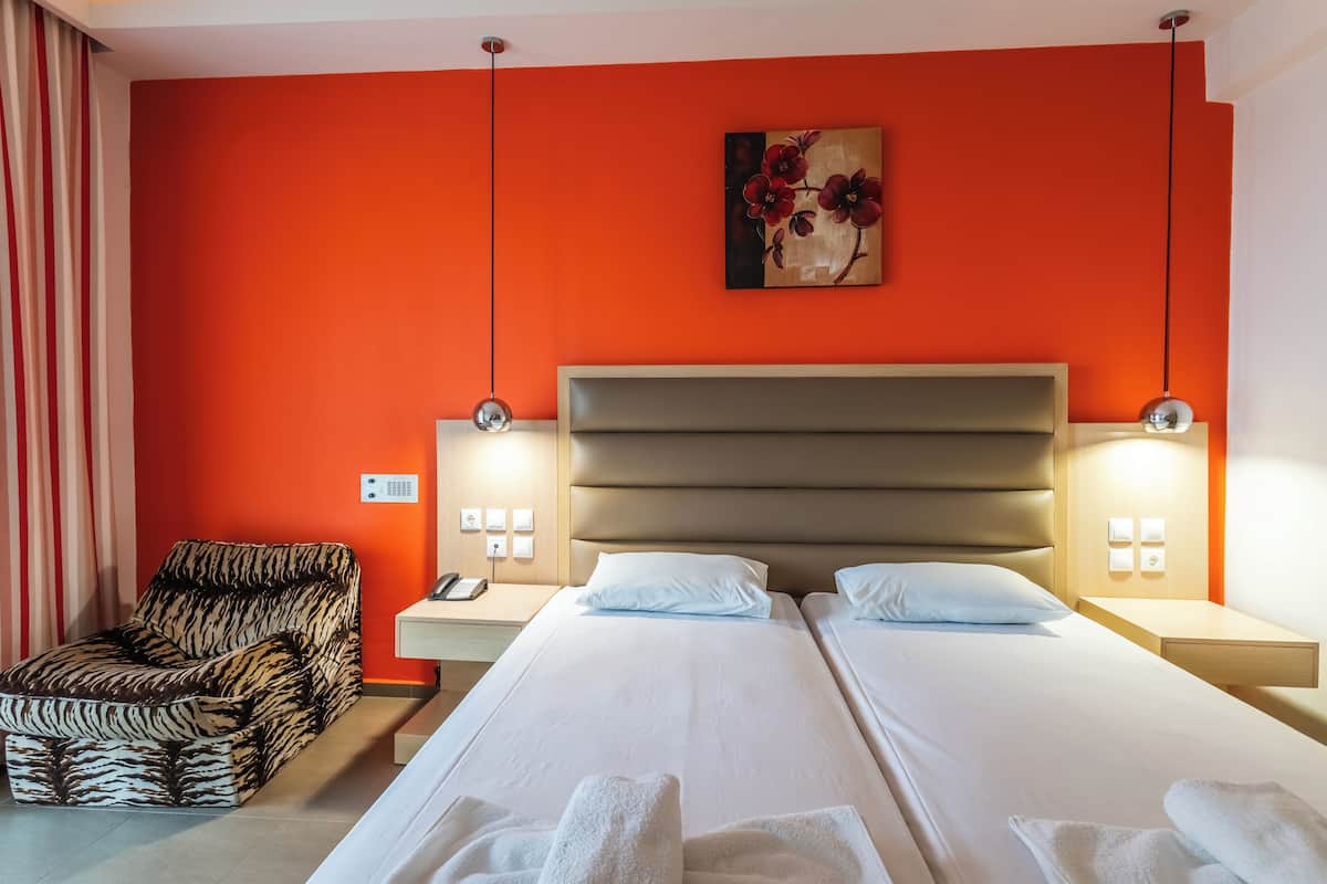 Habitación de hotel con dos camas, un sofá y un cuadro en la pared.