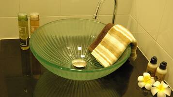 Un lavabo de vidrio verde con una toalla y artículos de aseo.