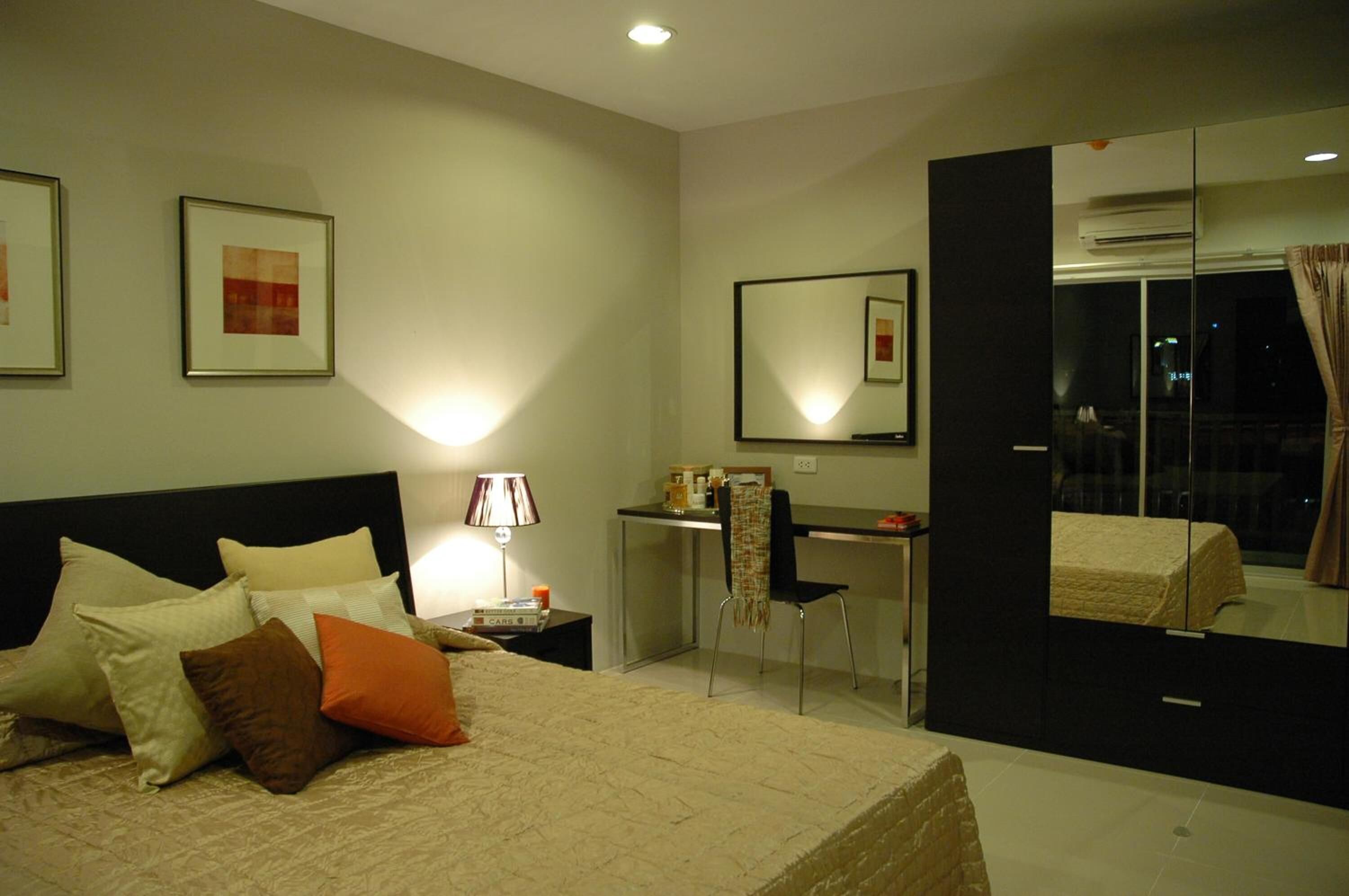 Habitació d'hotel amb llit, escriptori, cadira i un gran mirall.