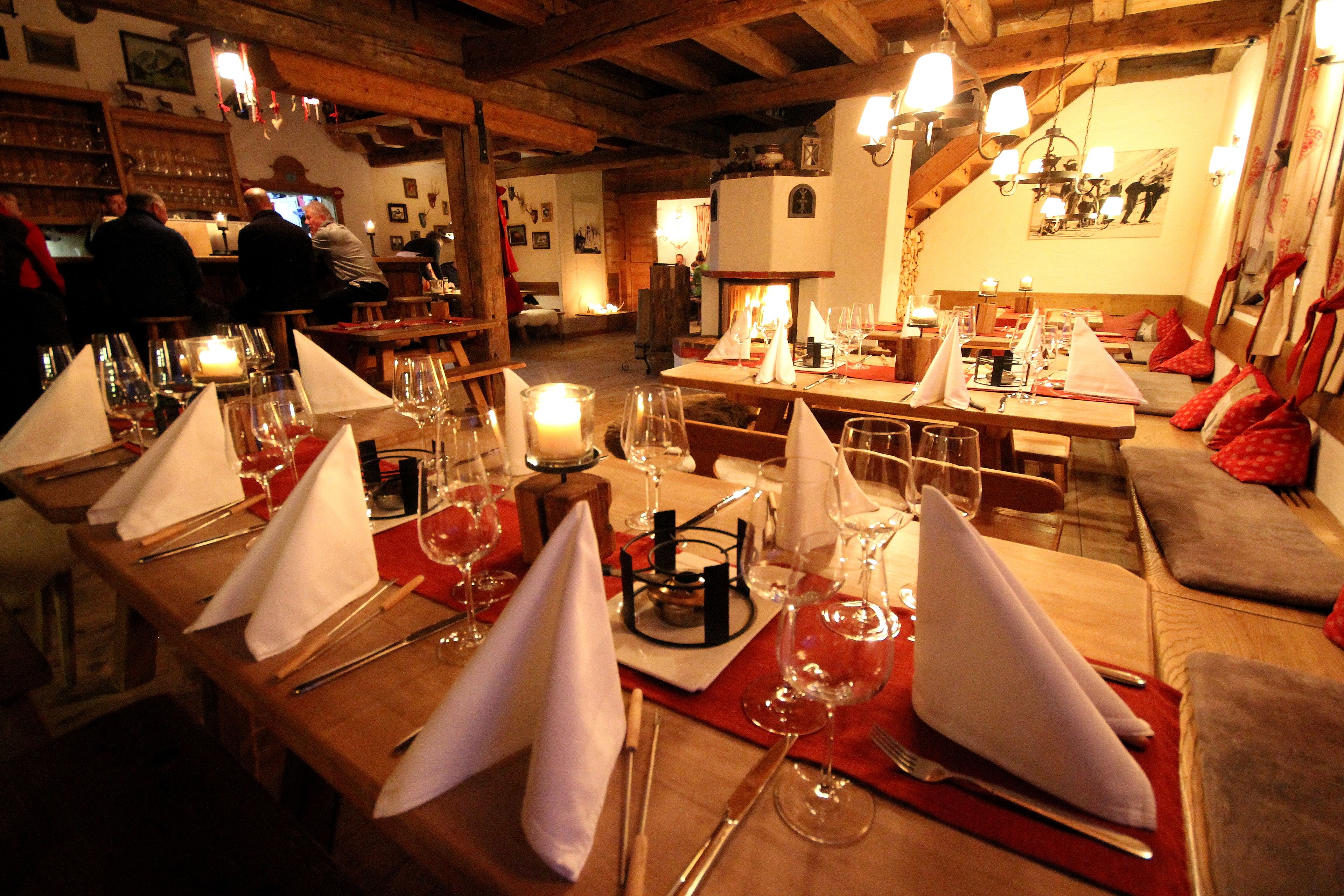 Een restaurant met houten tafels gedekt voor een diner, kaarsen en een gezellig interieur.