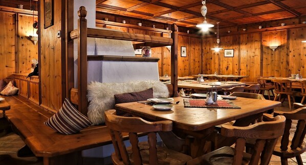 Ein gemütliches Restaurant mit Holzwänden und -bänken, mit einem zentralen Tisch und einem weißen, flauschigen Kissen.