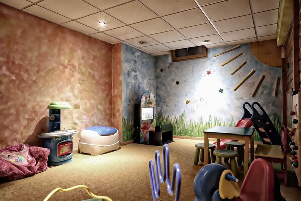 Una sala de juegos infantil con zona de recreación, una mesita y un sofá.