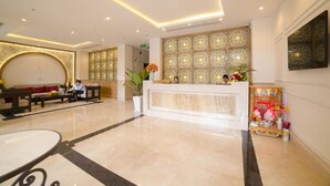 Een hotellobby met een receptiebalie, een zithoek en decoratieve elementen.