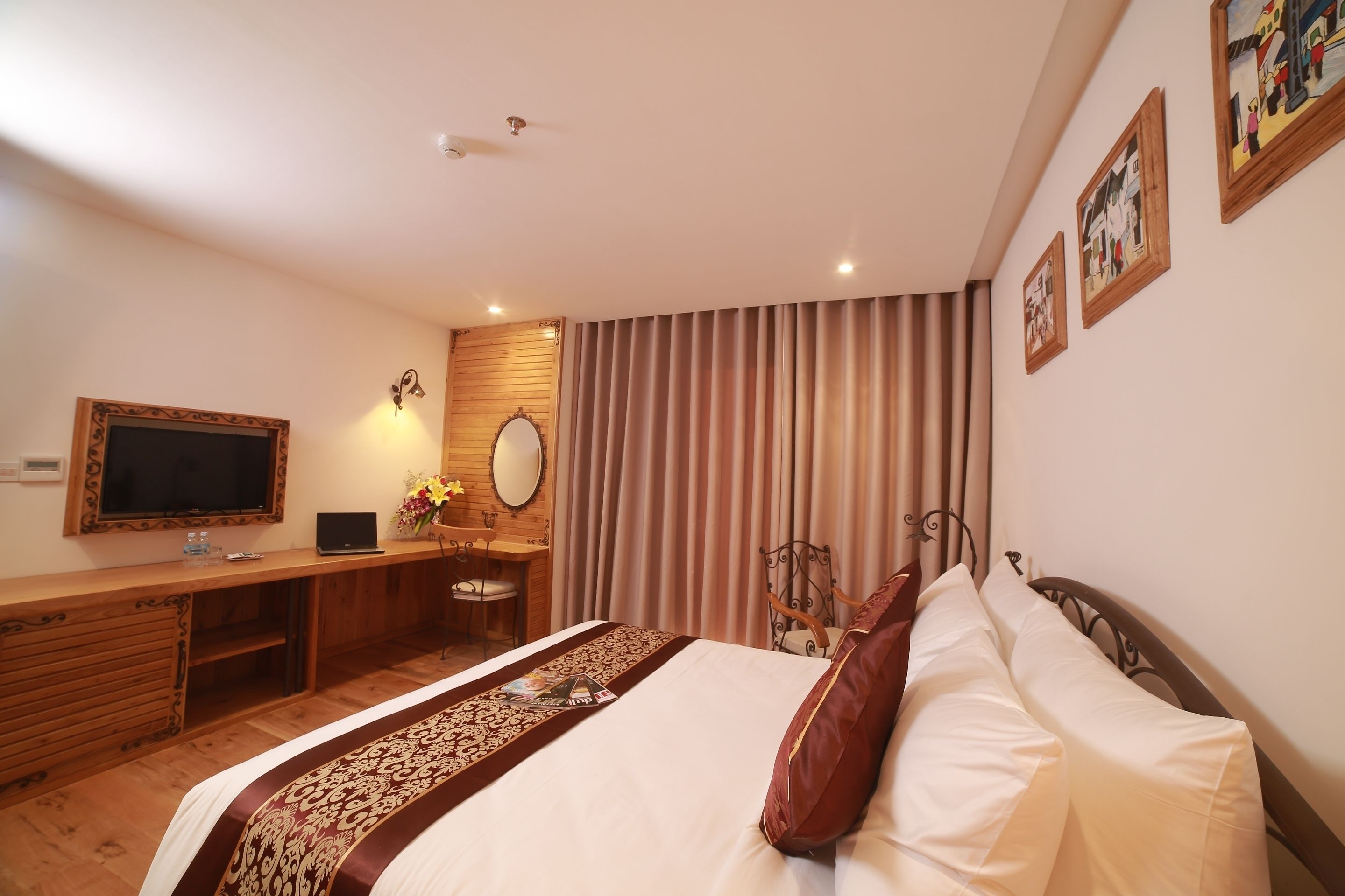 Una habitación de hotel con cama, escritorio, televisión y espejo.