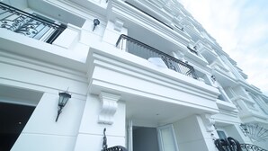 Een meerlaags gebouw met witte gevels, zwarte sierhekwerk balkon en decoratieve kolommen.