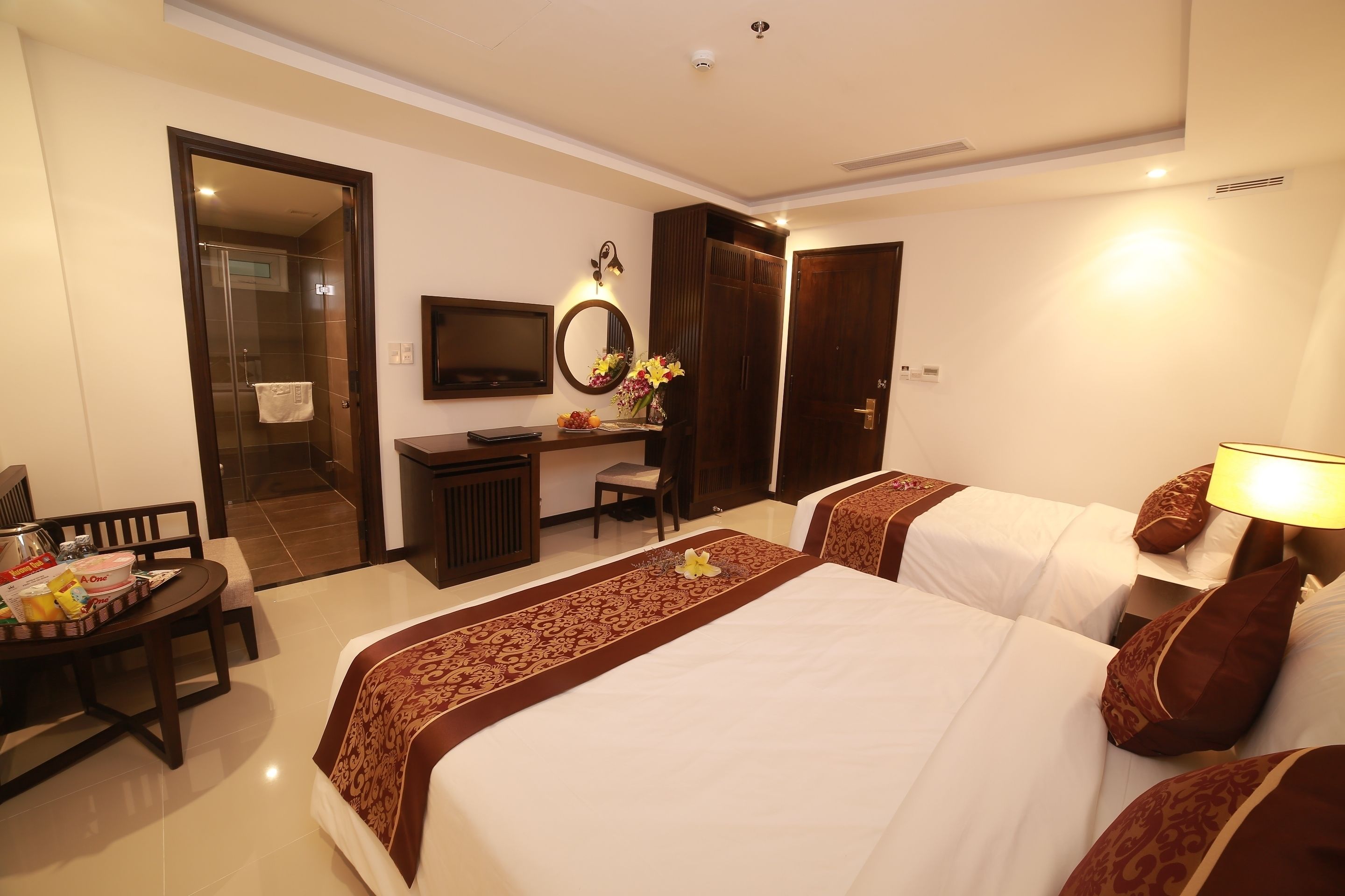 A hotel room with two beds, a desk, a chair, a TV, and a wardrobe.