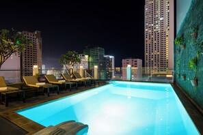 A rooftop pool with lounge chairs and a cityscape view at night. - Edele Hotel (Nha Trang)