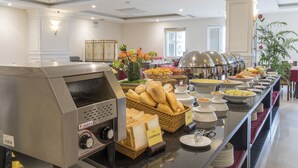 Een buffetopstelling met een bedieningsstation voor eten, broodmanden en diverse gerechten.