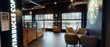 A Starbucks coffee shop interior with seating, a counter, and large windows.