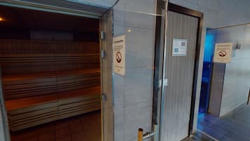 Een hotel lobby met een zithoek, een glazen deur en borden waarop staat dat drinkflessen niet zijn toegestaan.