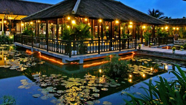 A thatched-roof structure with a pool and lily pads, surrounded by plants and lights. - Villa Hoa Su - Frangipani Village Resort (Da Nang)