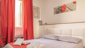 A hotel room with a bed, red curtains, a window, and a painting on the wall. - New Inn (Rome)