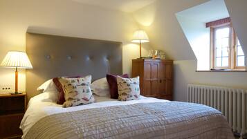 A bedroom with a large bed, two bedside lamps, a wooden cabinet, and a window with a view.